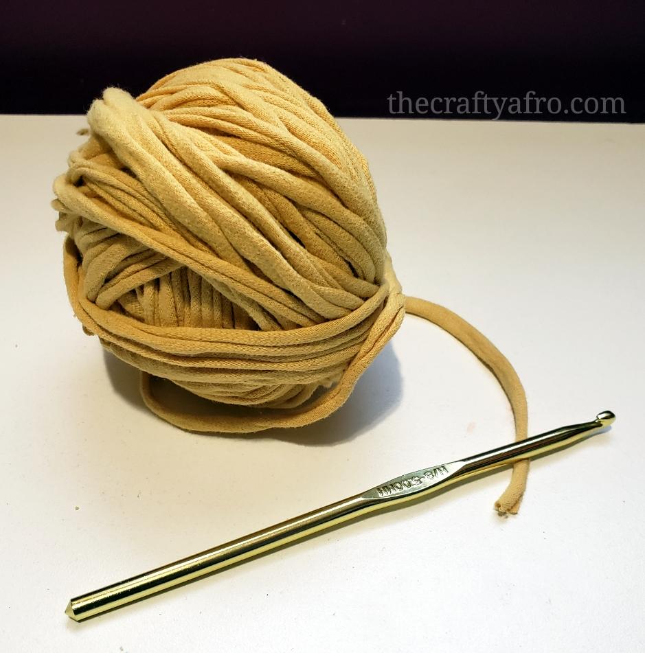 yellow ball of t-shirt yarn with a metal crochet hook.